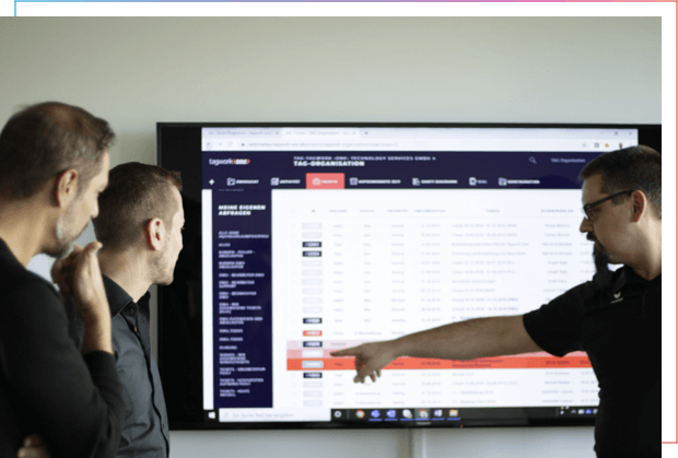 Drei Männer diskutieren über eine Analyse an einem Bildschirm. Ein Mann zeigt auf den Bildschirm.