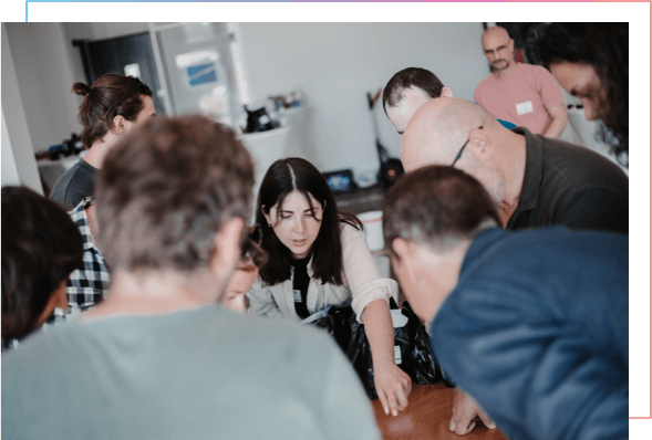 Das port-neo-Team steht um einen Tisch gebeugt und diskutiert und brainstormt gemeinsam.