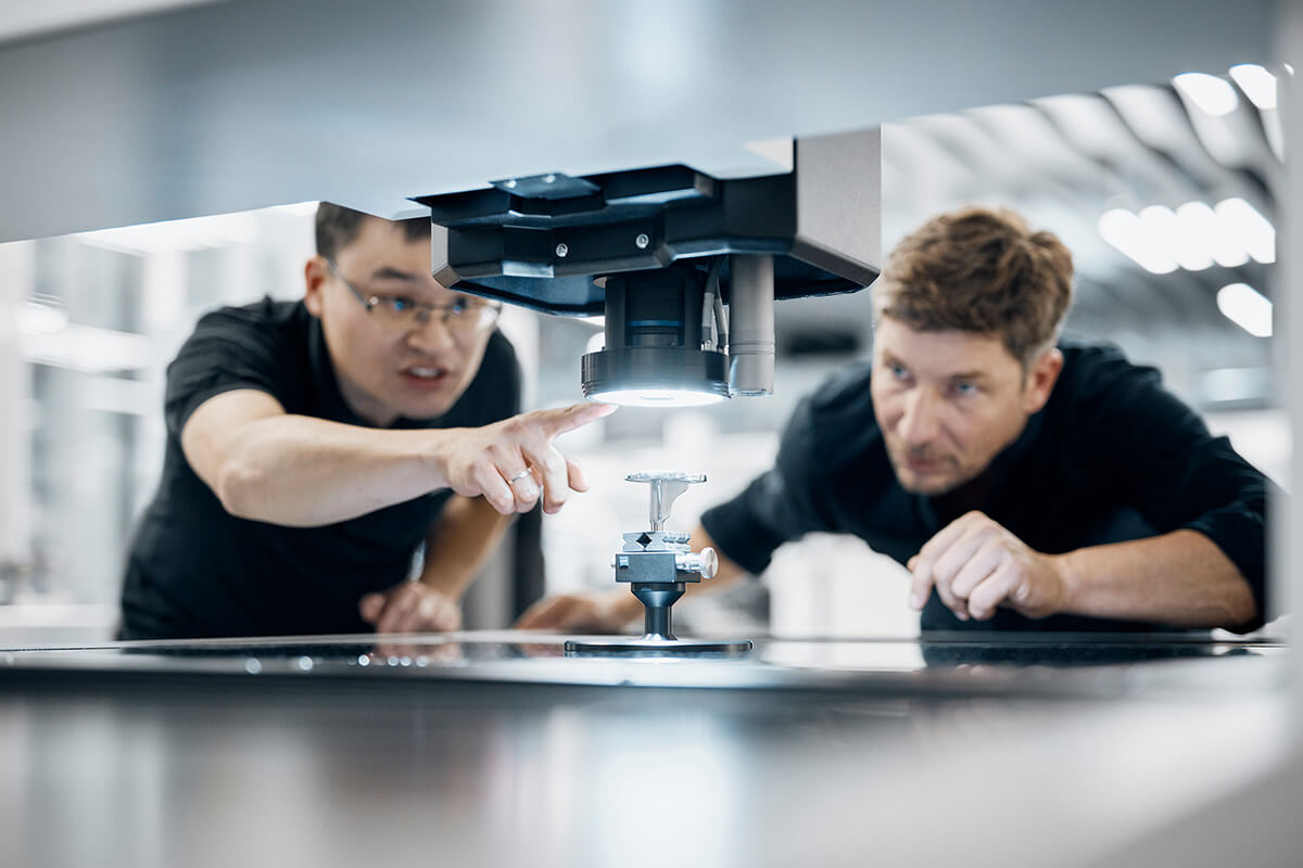 Zwei Zeiss Mitarbeiter blicken auf eine Maschine.