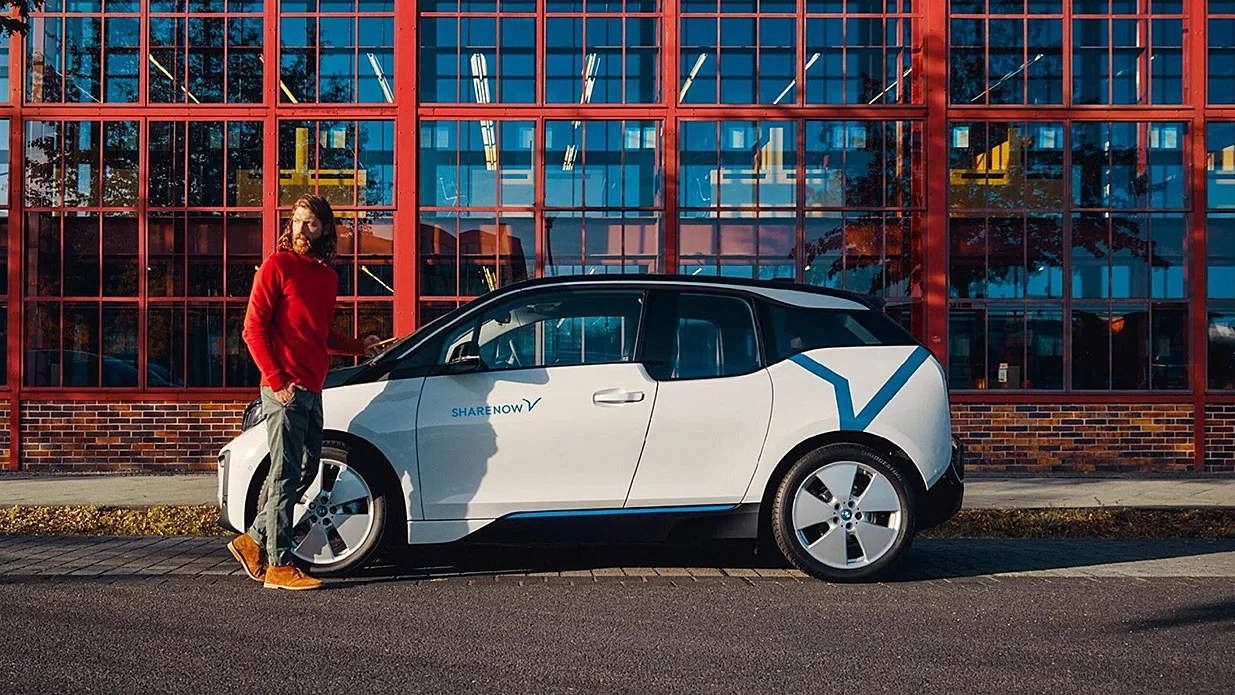 Mann steht vor weißem Auto und blickt sich um.