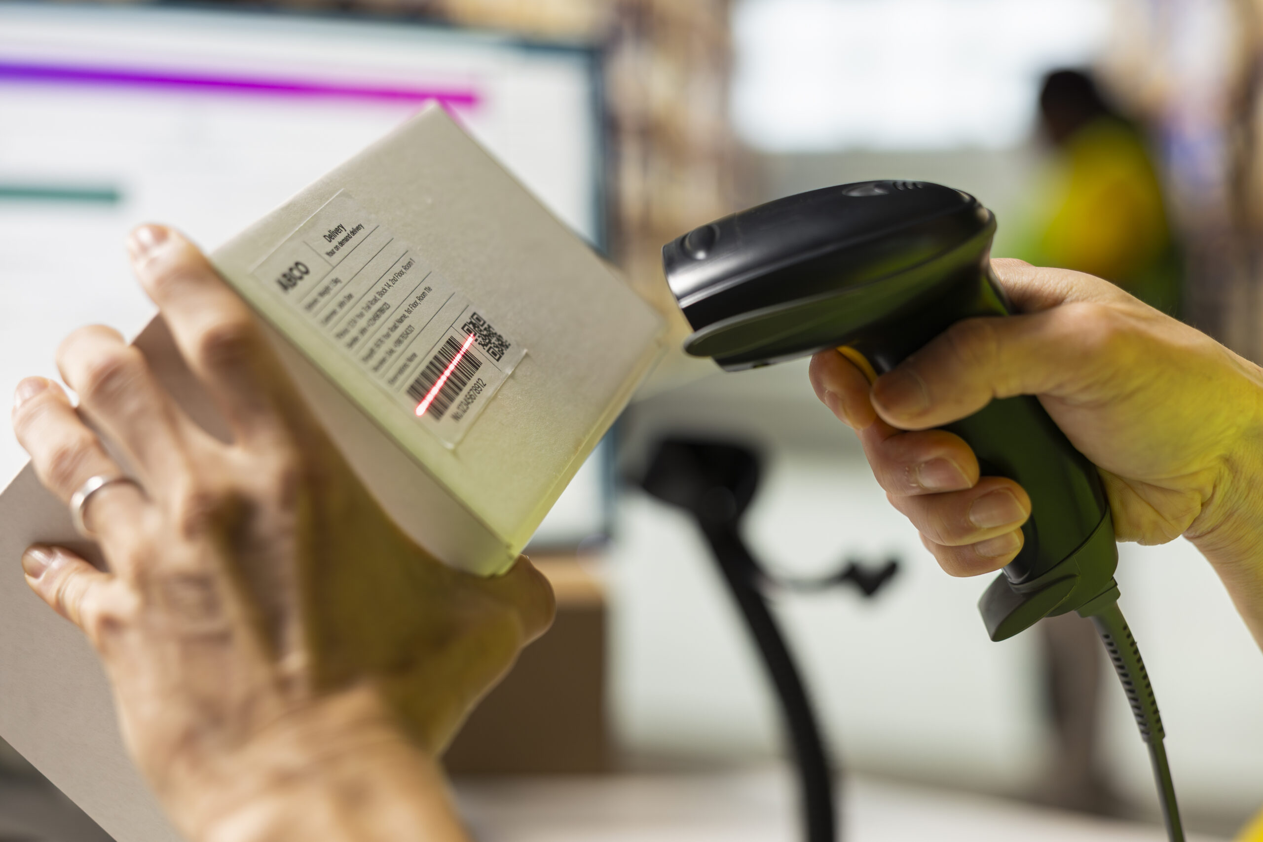 Nahaufnahme eines Mitarbeiters, der in einem Distributionszentrum Barcodes an Paketen scannt