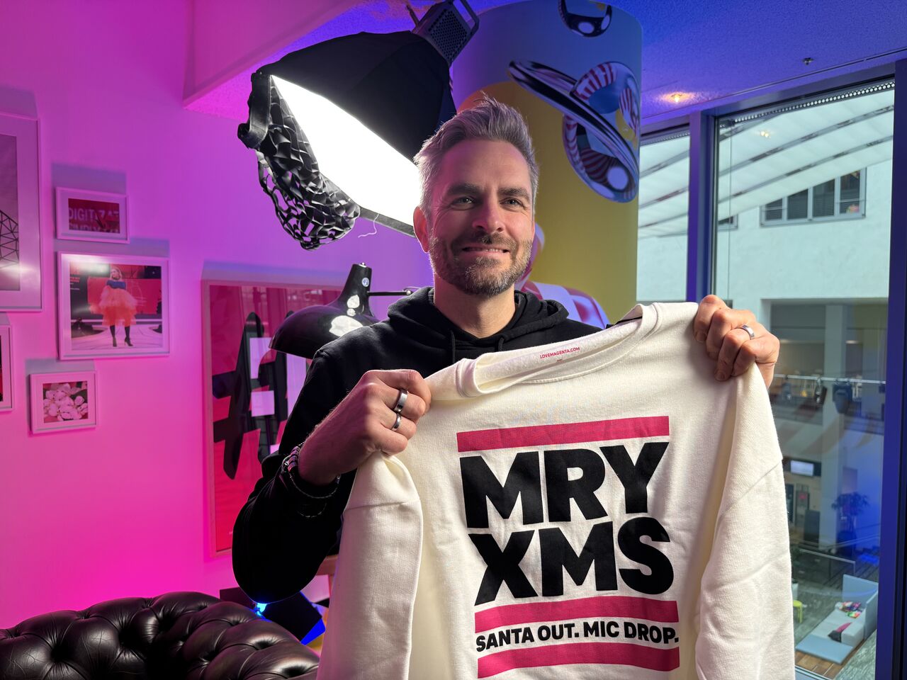 Kai Vorhölter hält Gastgeschenk weißen Weihnachtspulli hoch